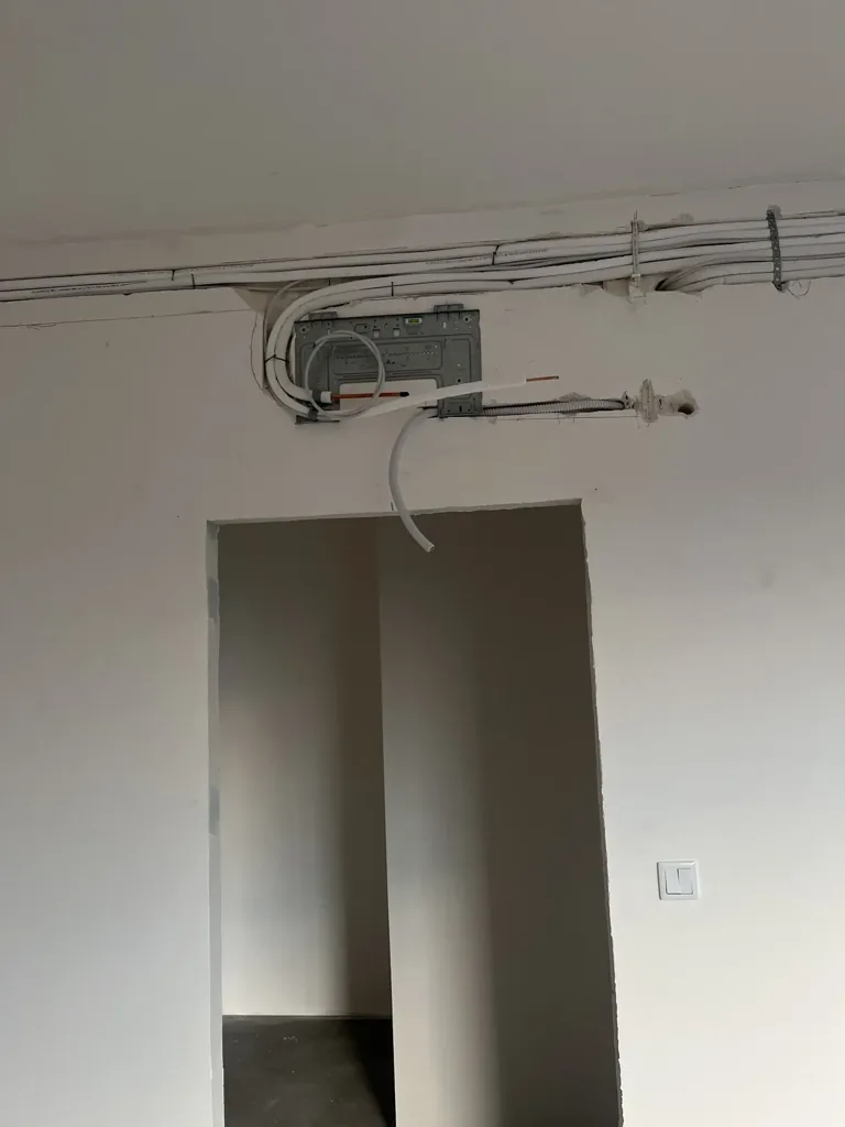 Przygotowana płyta montażowa i przewody instalacji nad otworem drzwiowym.